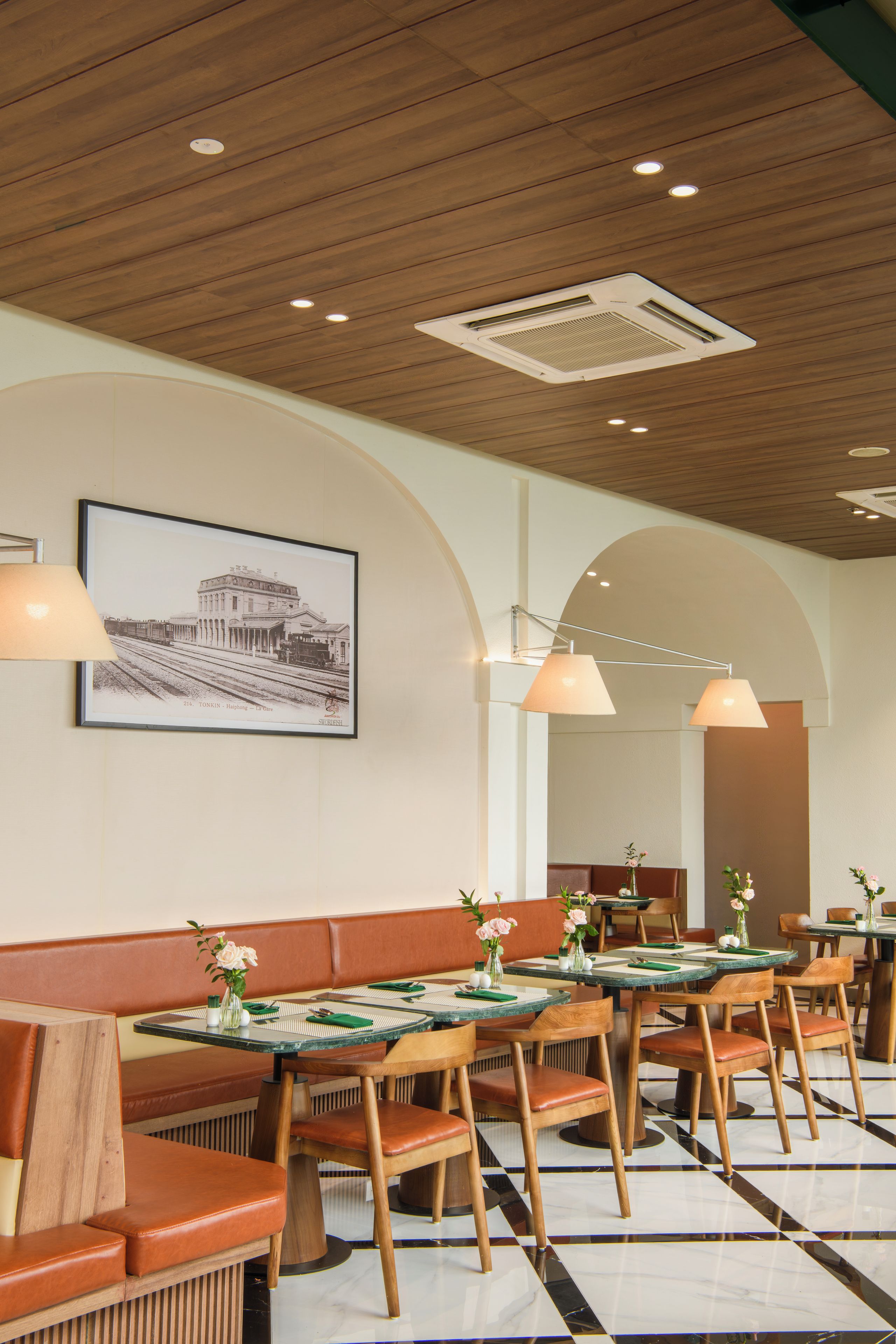 A restaurant interior with wooden ceiling, tables with green placemats, and leather booths.