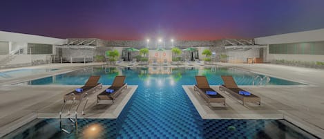 Una piscina al aire libre, sombrillas, sillones reclinables de piscina