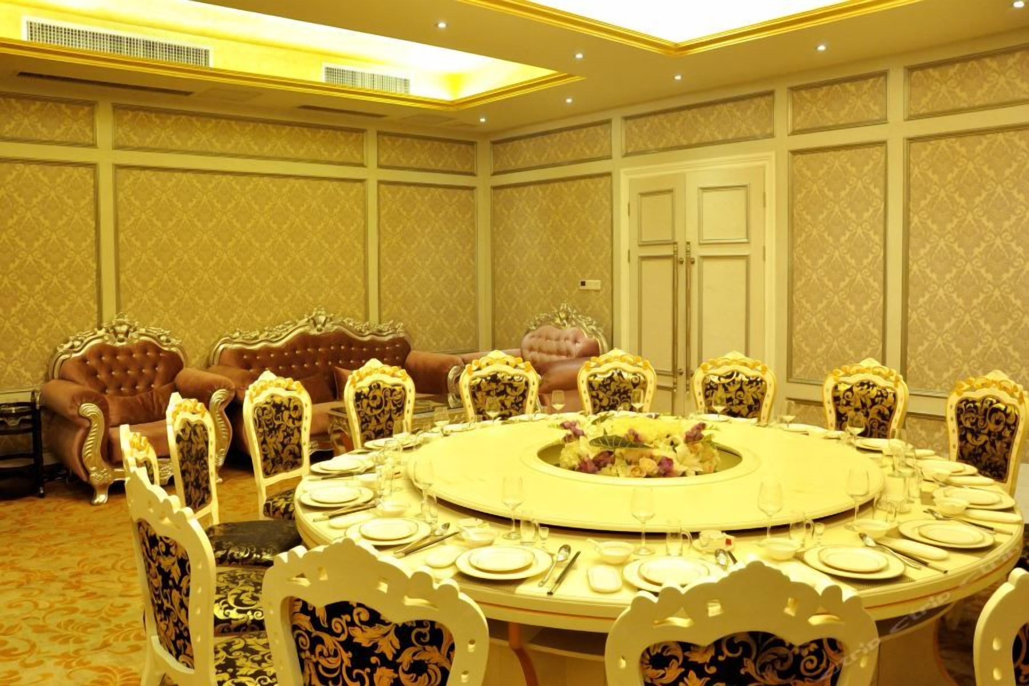 Uma sala de jantar formal com uma mesa redonda, cadeiras ornamentadas e um sofá luxuoso.