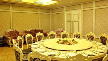 Uma sala de jantar formal com uma mesa redonda, cadeiras ornamentadas e um sofá luxuoso.