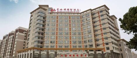 A multi-story hotel with a prominent entrance and a fountain in front.