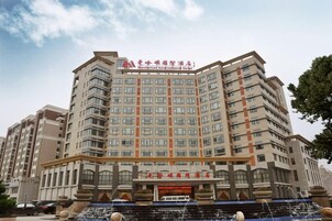 Un hotel de varios pisos con una entrada destacada y una fuente en primer plano.