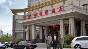 A hotel entrance with a modern architectural design, featuring a prominent overhang and a large entrance.