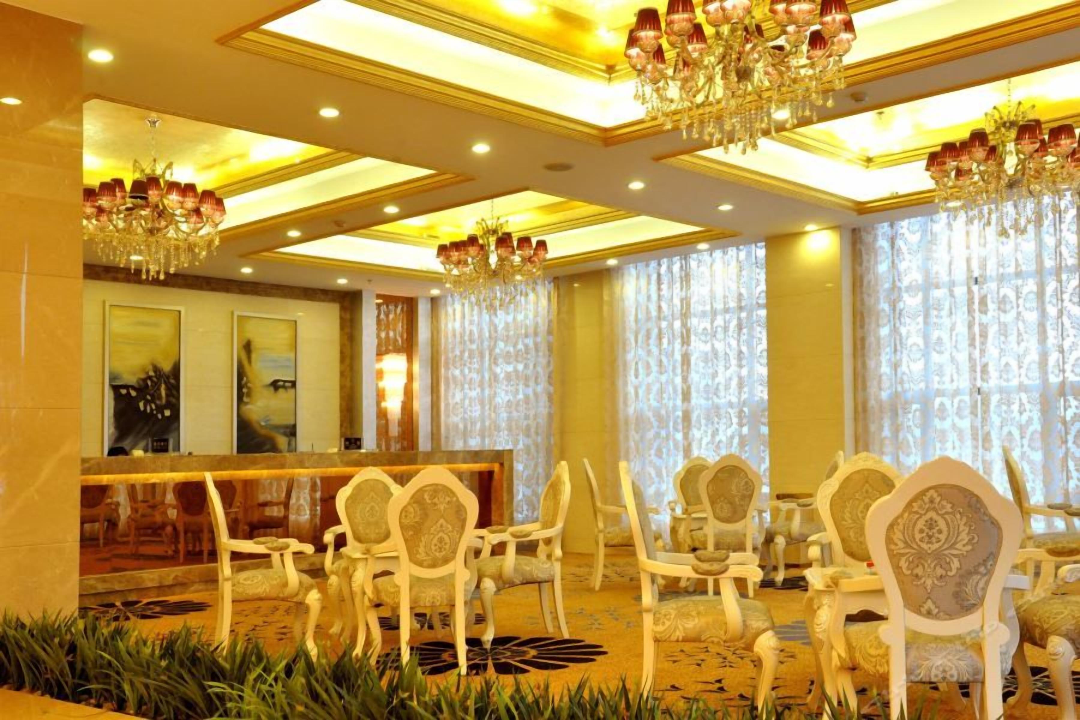Vestíbulo de hotel con mostrador de recepción, zona de estar y candelabros.