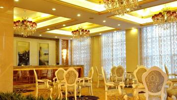 Vestíbulo de hotel con mostrador de recepción, zona de estar y candelabros.