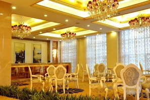 A hotel lobby with a reception desk, seating area, and chandeliers. - Manhattan International Hotel (Huaibei)