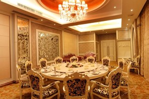 Un comedor formal con una mesa redonda, sillas ornamentadas y una araña.