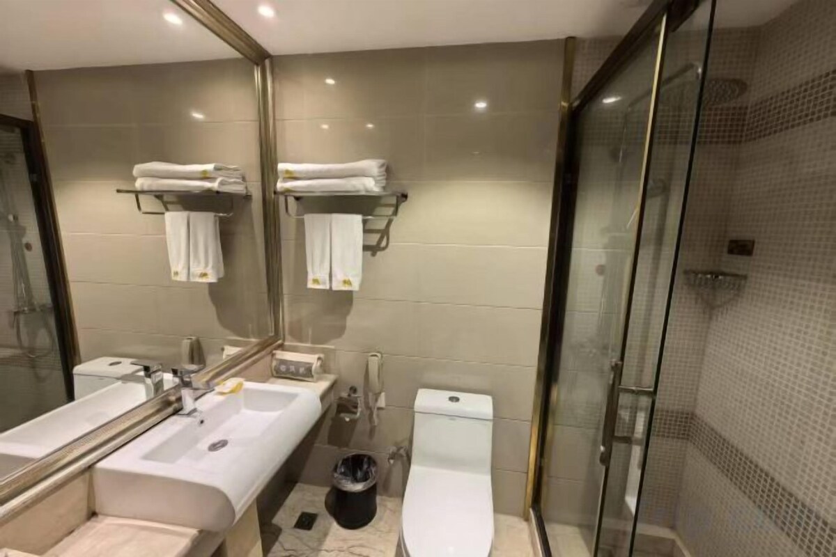 A modern bathroom with a glass shower enclosure, a dual sink vanity, and a toilet.