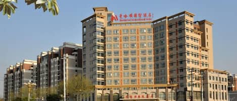 A multi-story hotel with a prominent sign, a large entrance, and a parking area.