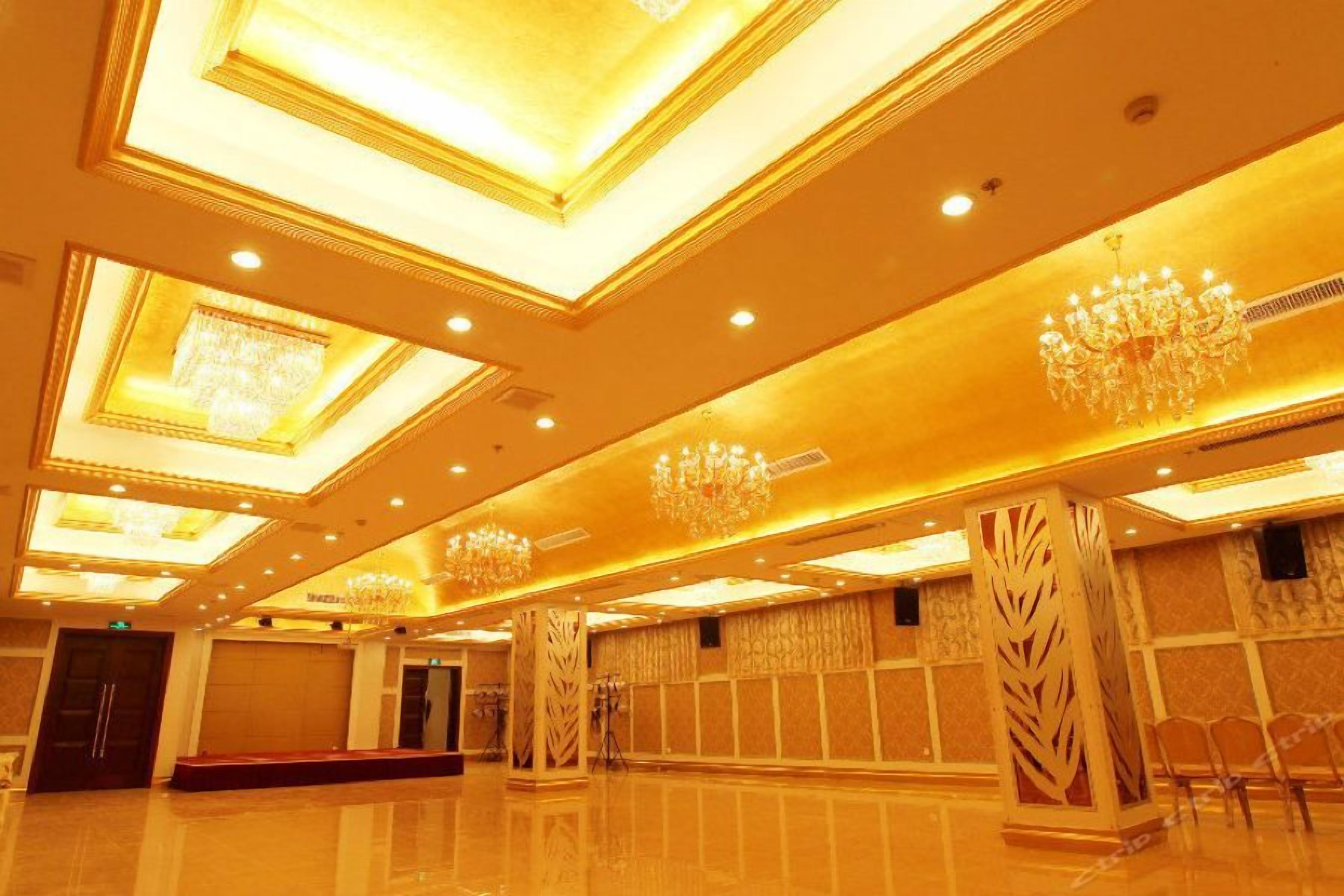 Un amplio vestíbulo de hotel con techos altos, candelabros y suelo pulido.