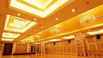 Un amplio vestíbulo de hotel con techos altos, candelabros y suelo pulido.