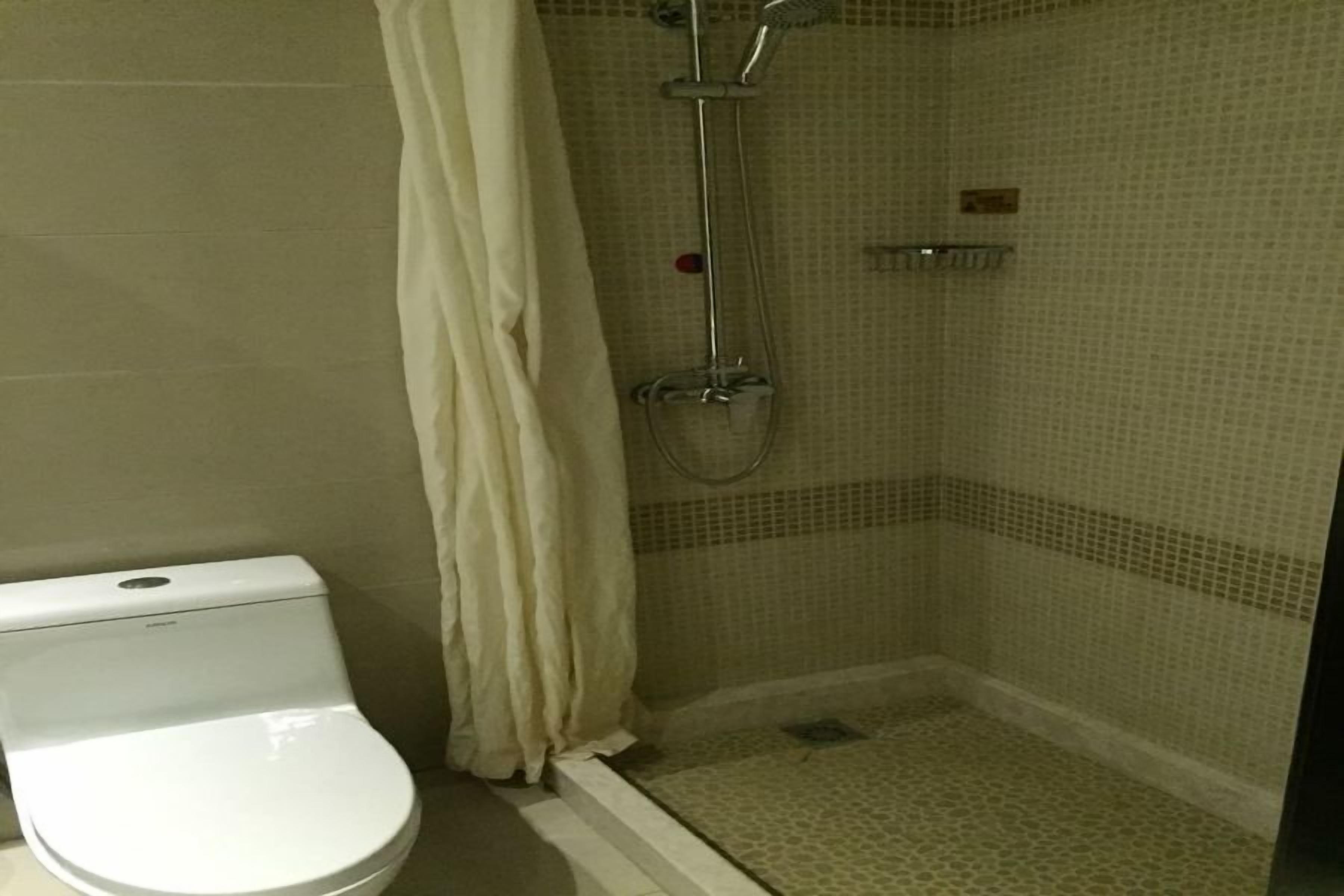 A bathroom with a toilet, a shower with a glass door, and tiled walls.