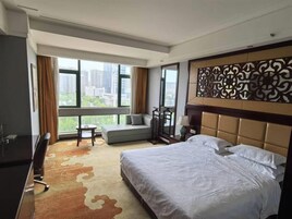 Habitación de hotel con una cama grande, un sofá, un escritorio y vistas de la ciudad.