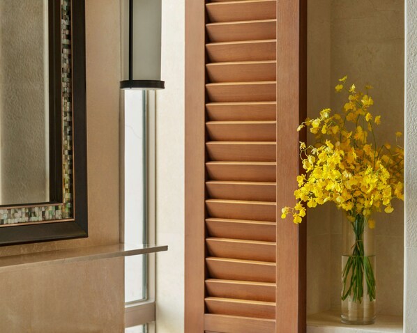 A room with a wooden slatted wall, a glass door, and a vase with yellow flowers. - Shangri-La Sanya (Sanya)