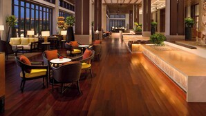 Un hall amplio con suelo de madera, asientos cómodos y ventanas grandes.