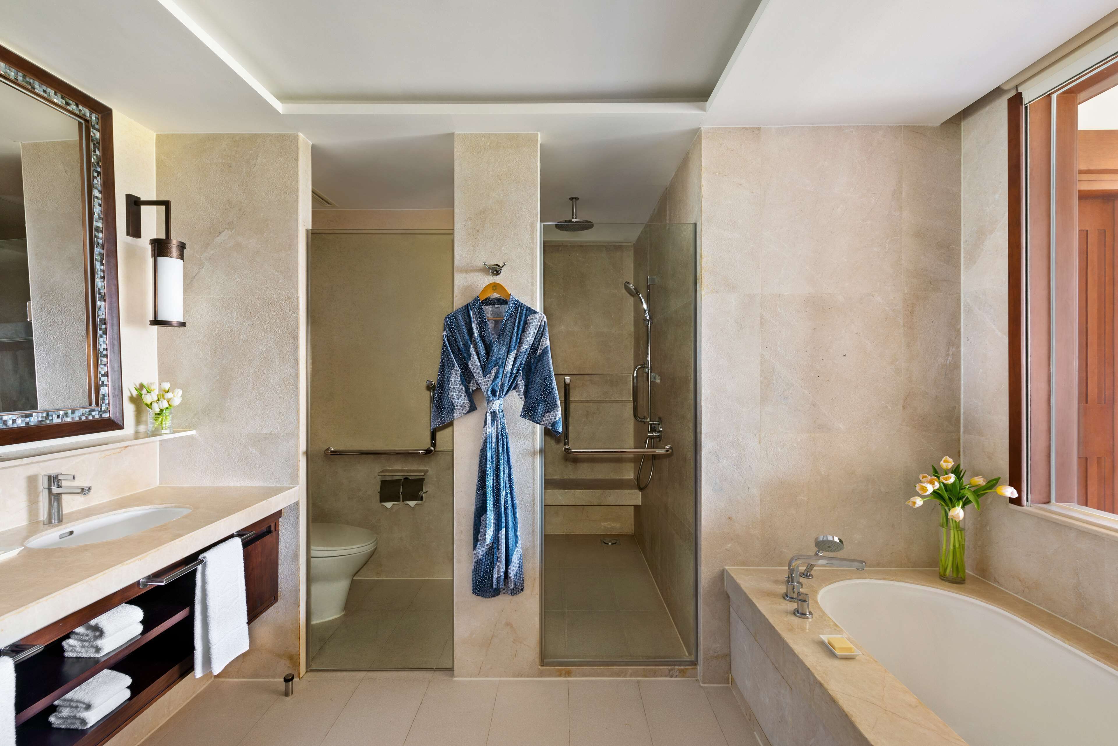 Un baño moderno con un espejo grande, una bañera, una ducha y un inodoro.