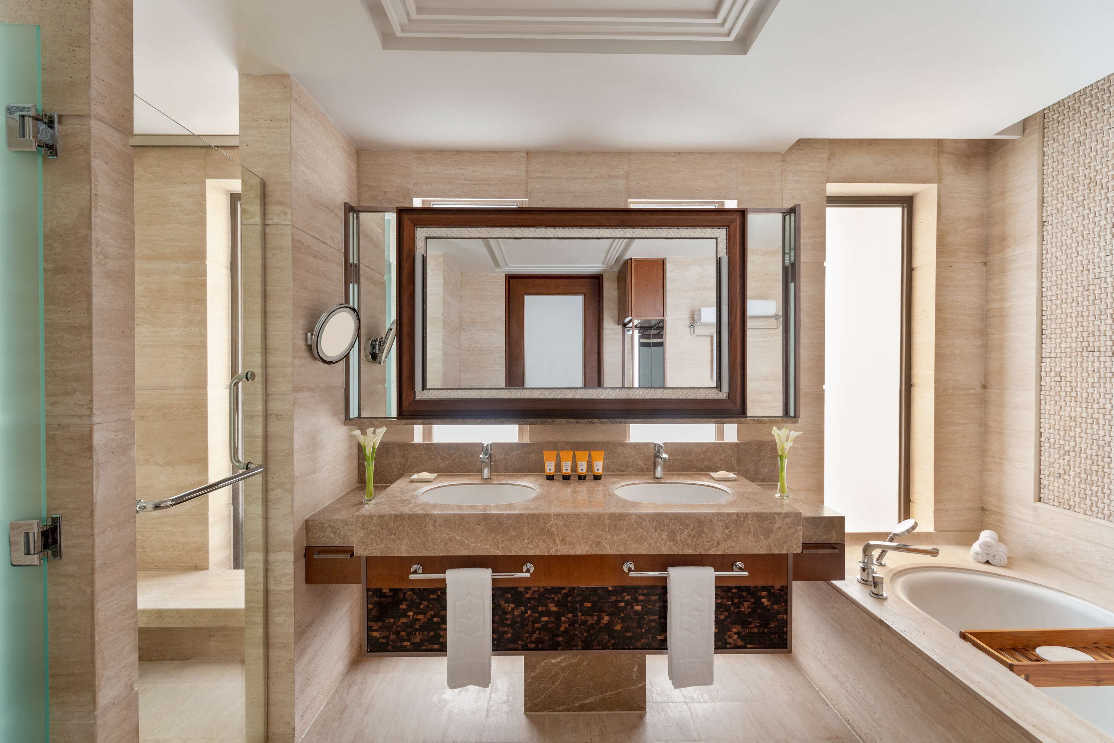 Un baño moderno con dos lavamanos, un espejo grande y una bañera.