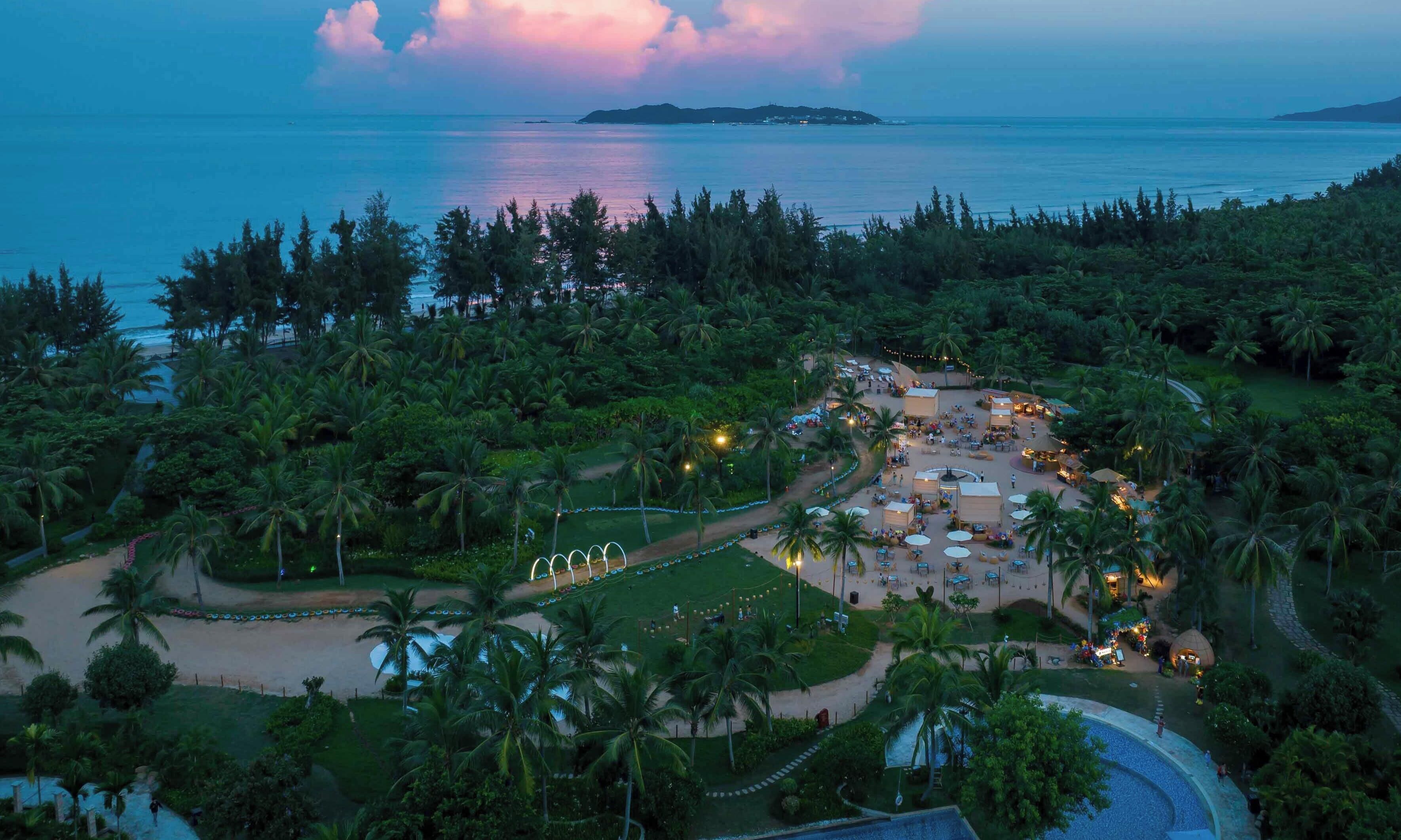 Vista aérea de un resort con playa, palmeras y piscina.