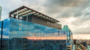 A JW Marriott hotel with a modern glass facade, large windows, and a prominent rooftop structure.