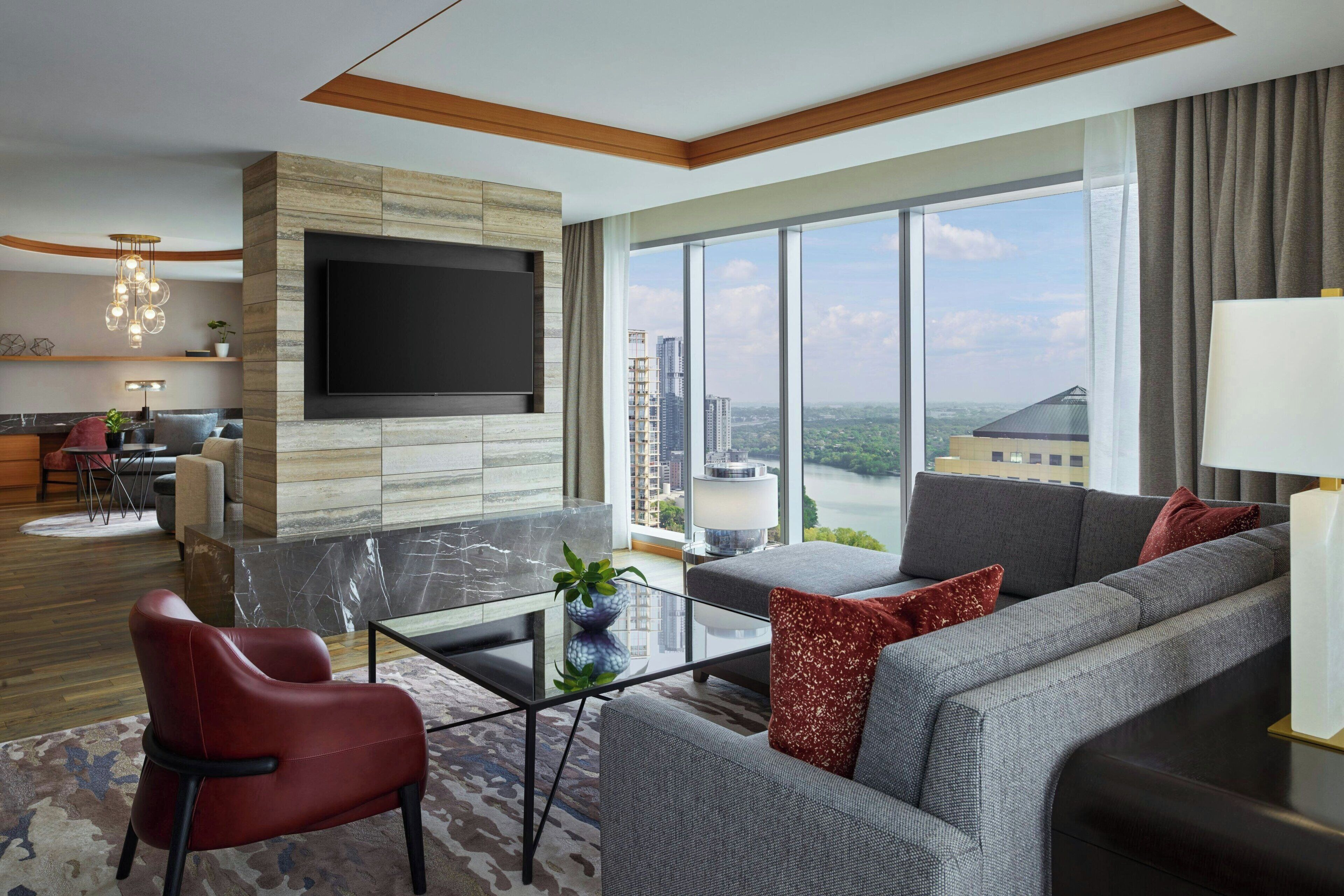 Una sala de estar moderna con un televisor grande, asientos cómodos, una mesa de centro de vidrio y vistas a la ciudad.