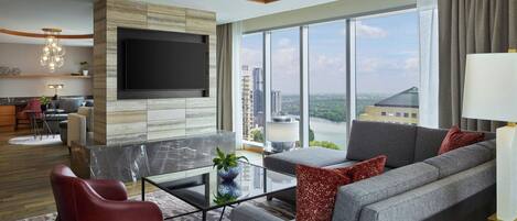 Una sala de estar moderna con un televisor grande, asientos cómodos, una mesa de centro de vidrio y vistas a la ciudad.