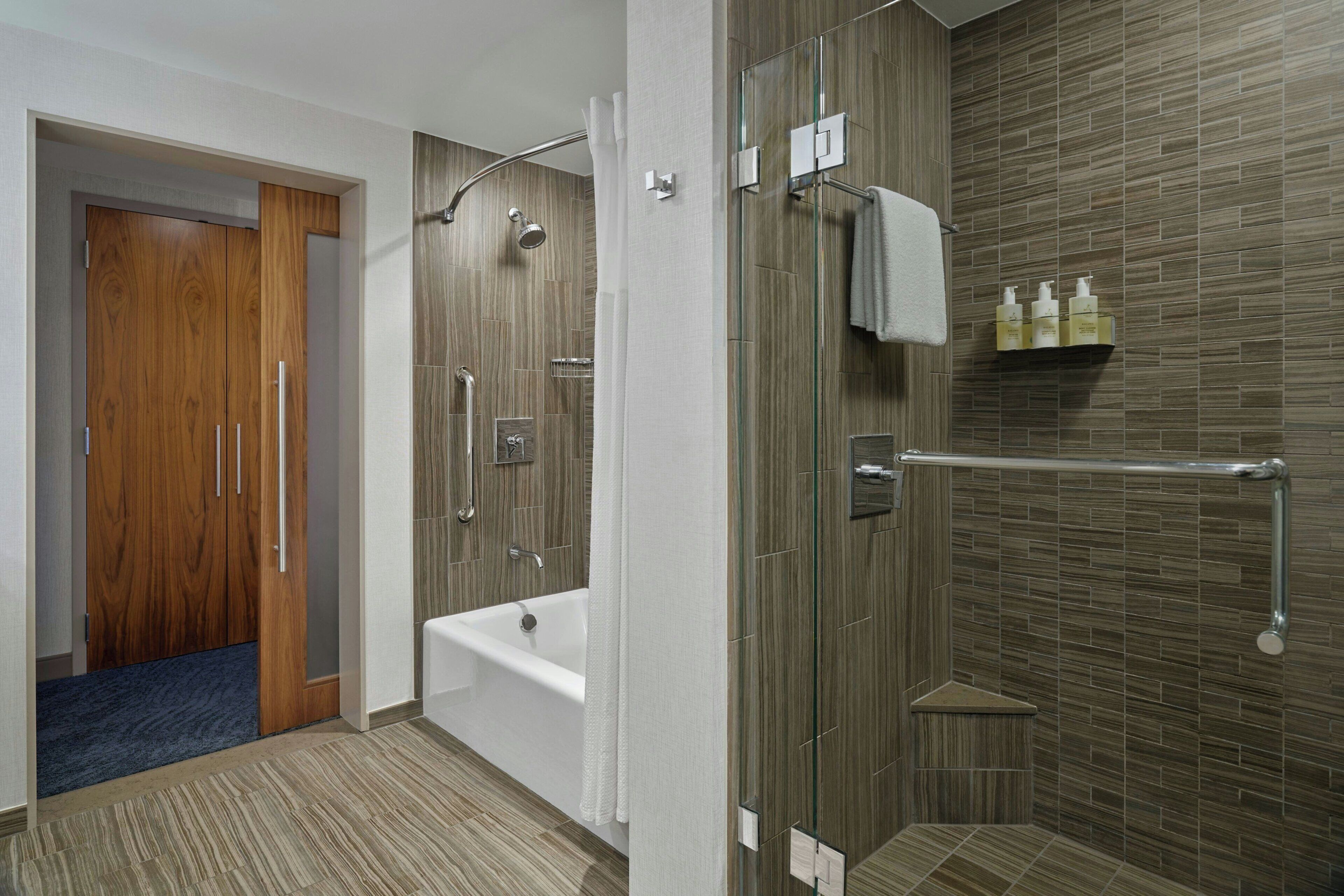 A modern bathroom with a shower, bathtub, and a towel rack.