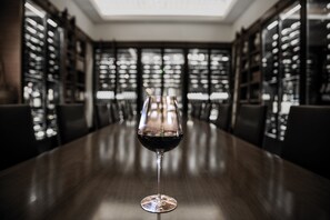 A wine glass on a wooden table in a room with bookshelves.