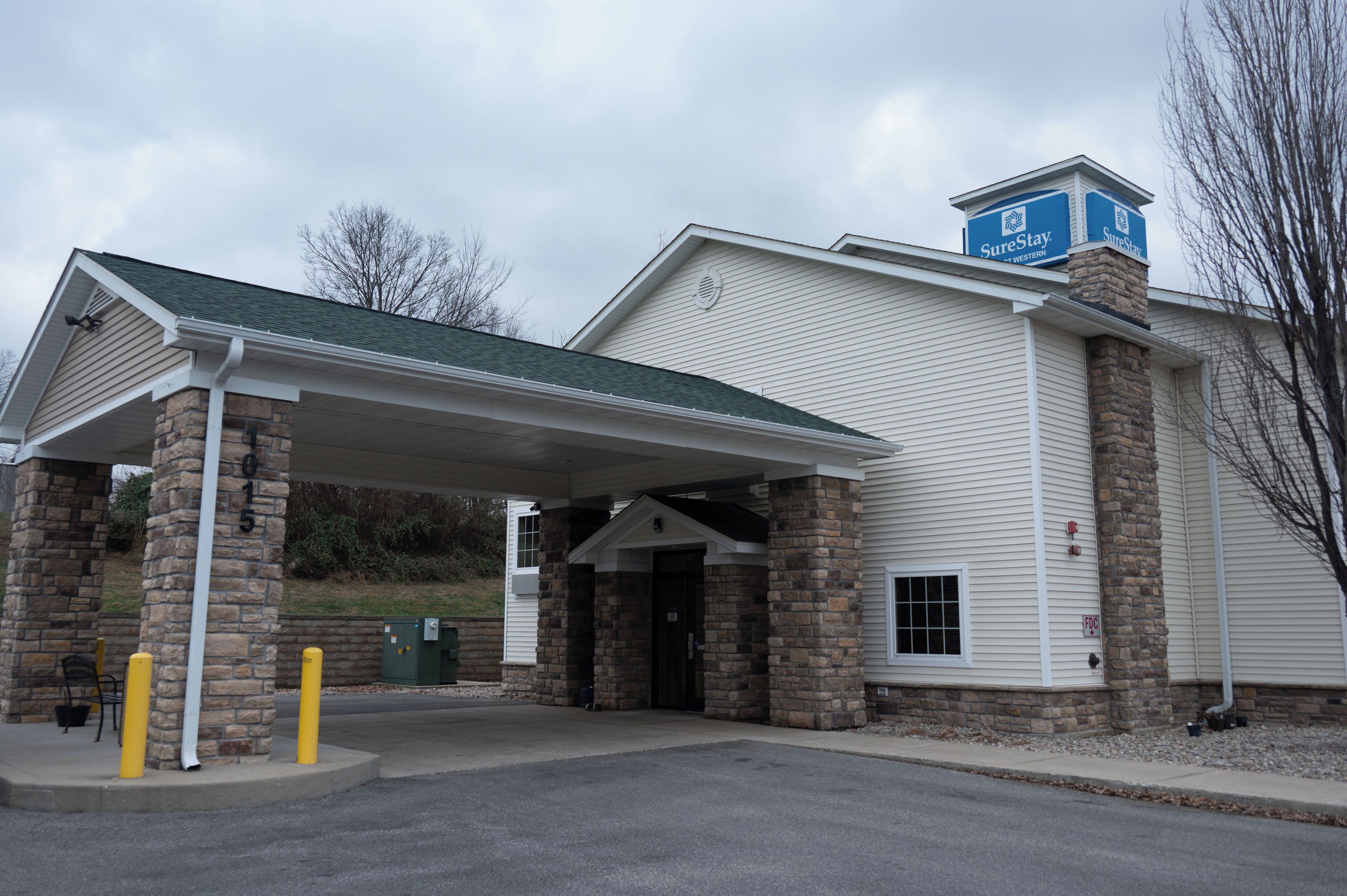 Un hôtel doté d’une entrée couverte, de piliers en pierre et d’une enseigne indiquant qu’il fait partie du réseau SureStay.