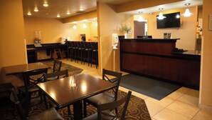 A restaurant with tables and chairs, a counter, and a television mounted on the wall.