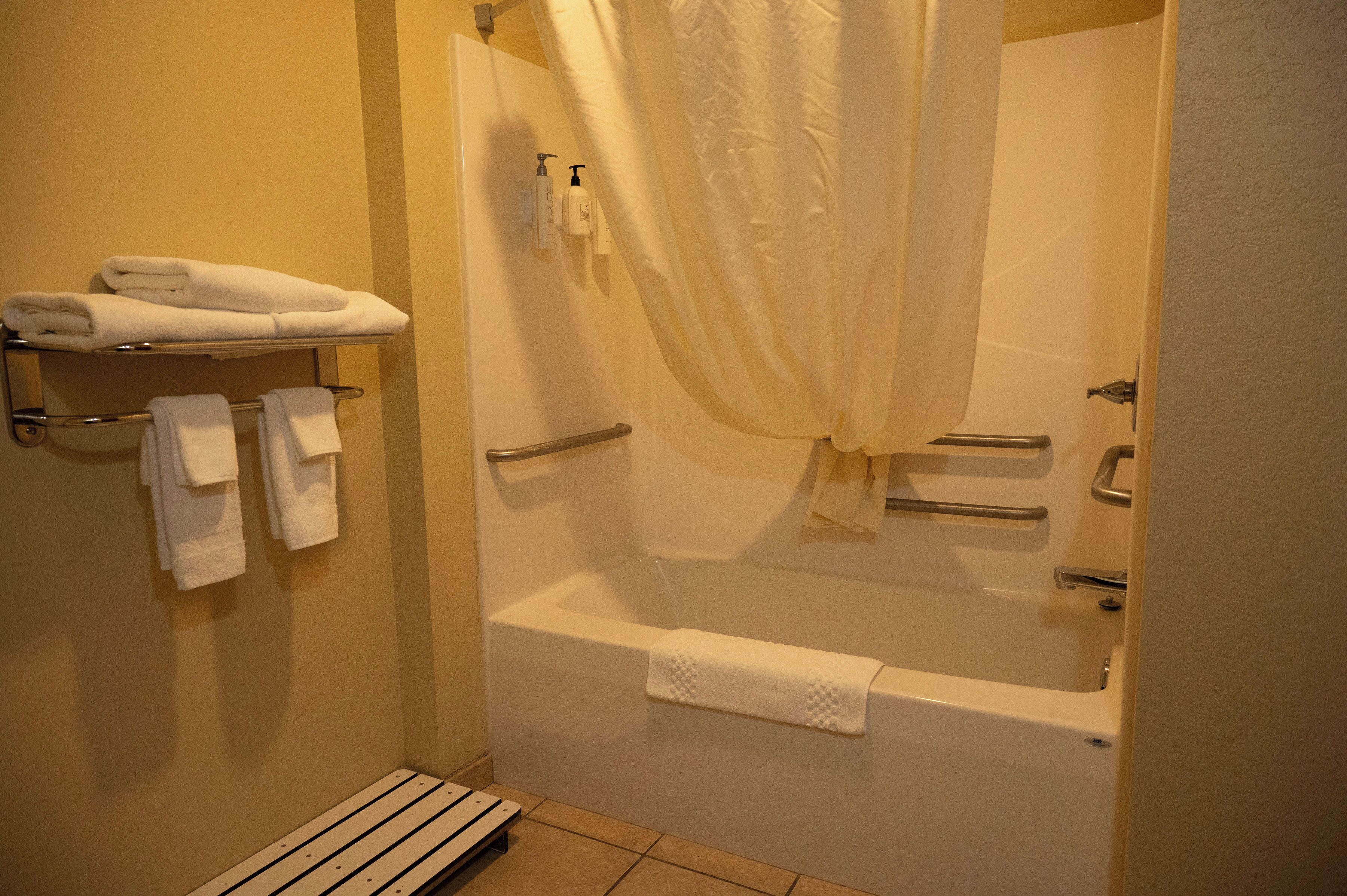 A bathroom with a bathtub, a shower curtain, and a towel rack with towels.