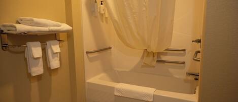 A bathroom with a bathtub, a shower curtain, and a towel rack with towels.
