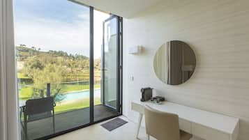 A modern room with a sliding glass door leading to a balcony, a white desk, a chair, and a round mirror on the wall.