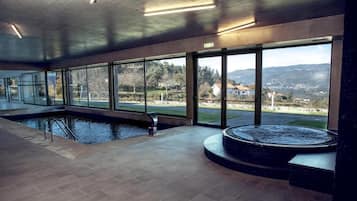 A large indoor swimming pool with clear views of the surrounding landscape through large windows.