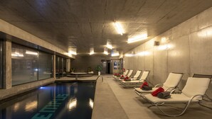 Una piscina con la palabra 'TENNIS' en el suelo, rodeada de sillas de descanso y toallas.