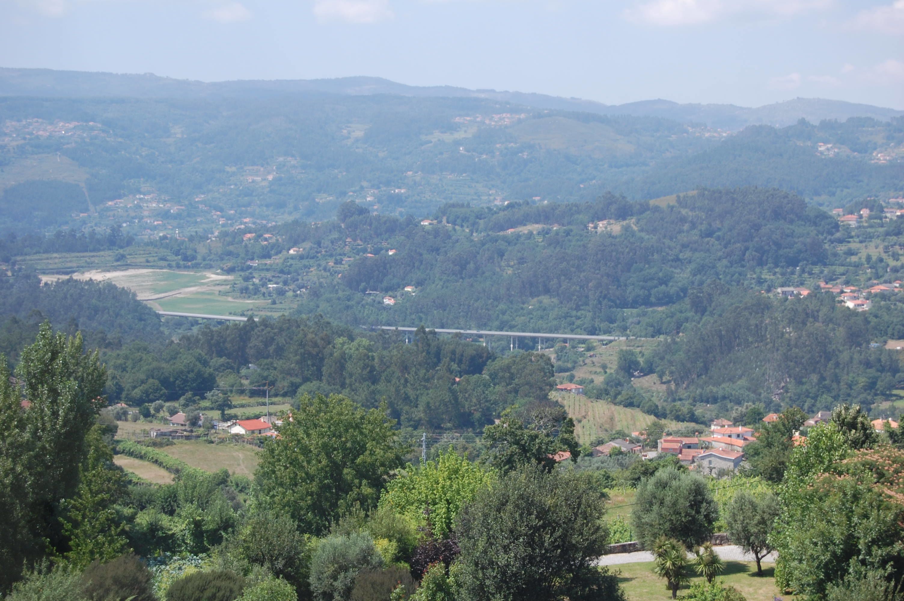 Paisaje rural con un puente, casas y vegetación.