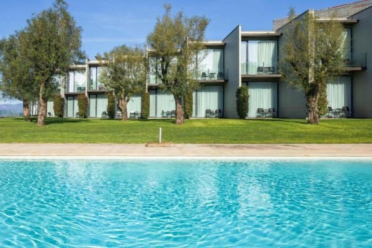 A hotel with a swimming pool, multiple buildings, and trees.