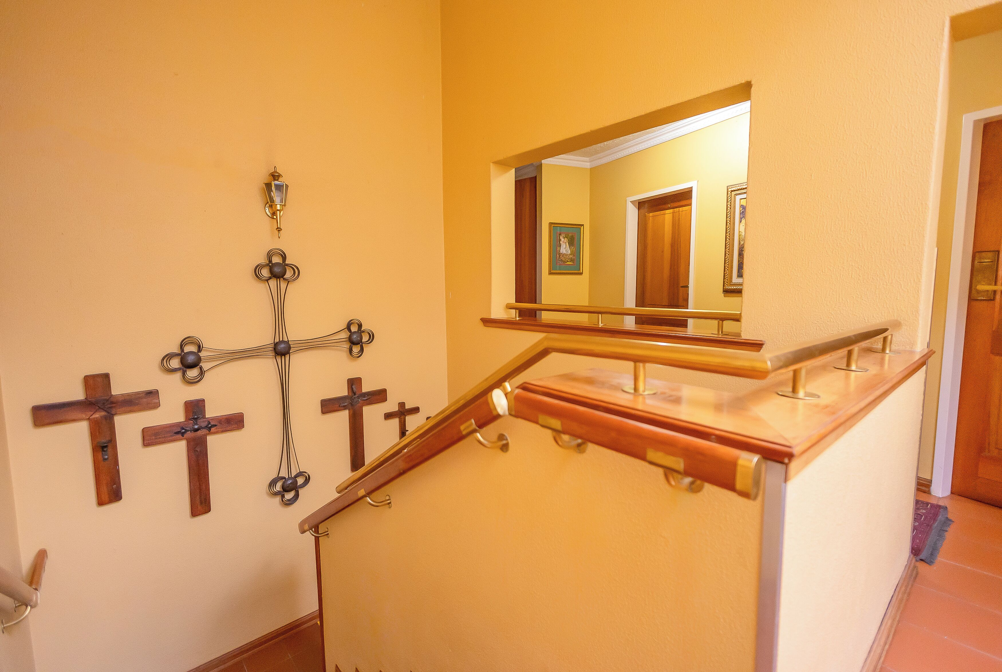 Una escalera con barandas de madera y un espejo fijado a la pared.