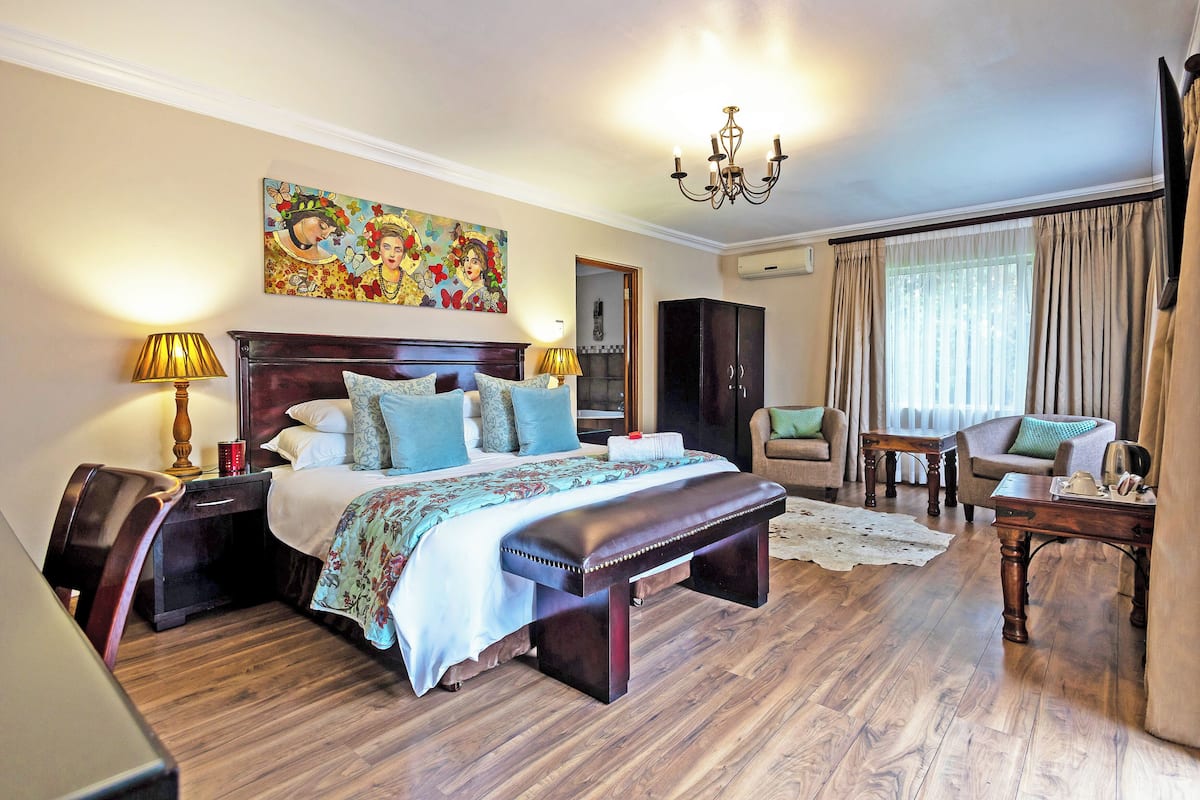 A well-furnished bedroom with a large bed, bedside tables, a bench, a sofa, and a chair.