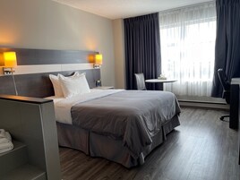 Quarto de hotel com uma cama grande, uma mesa de escritório, uma cadeira e uma pequena mesa.