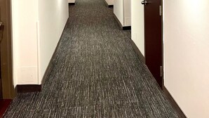 A long, narrow hallway with carpeted floors, wooden ceiling beams, and doors on both sides. - Auberge de la Gare (Gatineau)