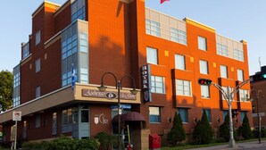 A multi-story hotel with a red brick facade, large windows, and a Canadian flag. - Auberge de la Gare (Gatineau)