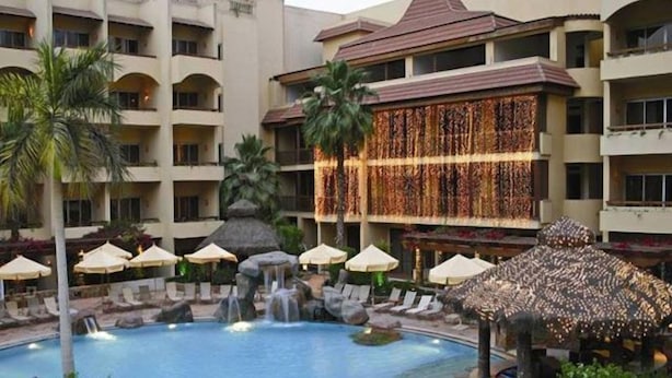 A hotel with a swimming pool, lounge chairs, umbrellas, and a waterfall. - Amarante Pyramids Hotel (Giza)