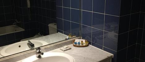 Un baño con un lavabo blanco, un espejo y una pared con azulejos azules.