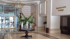 A lobby with a round table, potted plants, and a sign reading "Rendez-vous Lounge". - Amarante Pyramids Hotel (Giza)