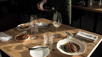 Un tavolo da pranzo con piatti di cibo, bicchieri da vino e una bottiglia che viene versata in un bicchiere.