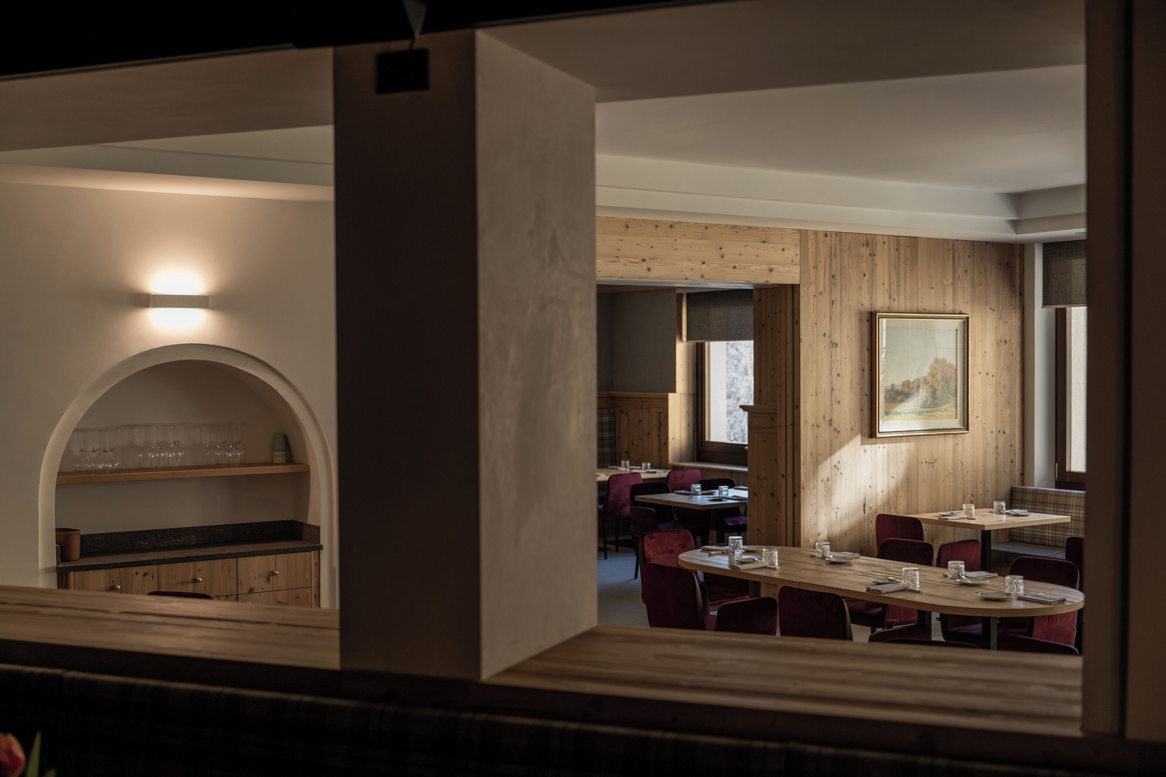 A restaurant with a wooden interior, tables set for dining, and a painting on the wall.