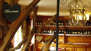 A rustic interior with wooden beams, a hanging lantern, and a wall of wine bottles. - Hotel Lysjoch (Gressoney-la-Trinite)