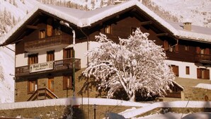 A traditional wooden chalet with a balcony, surrounded by snow-covered mountains. - Hotel Lysjoch (Gressoney-la-Trinite)