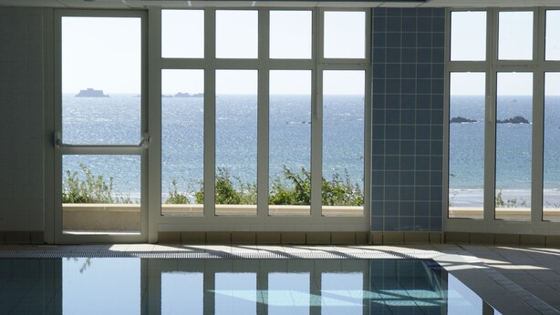 A swimming pool with a view of the sea through large windows. - Résidence Reine Marine (Saint-Malo)