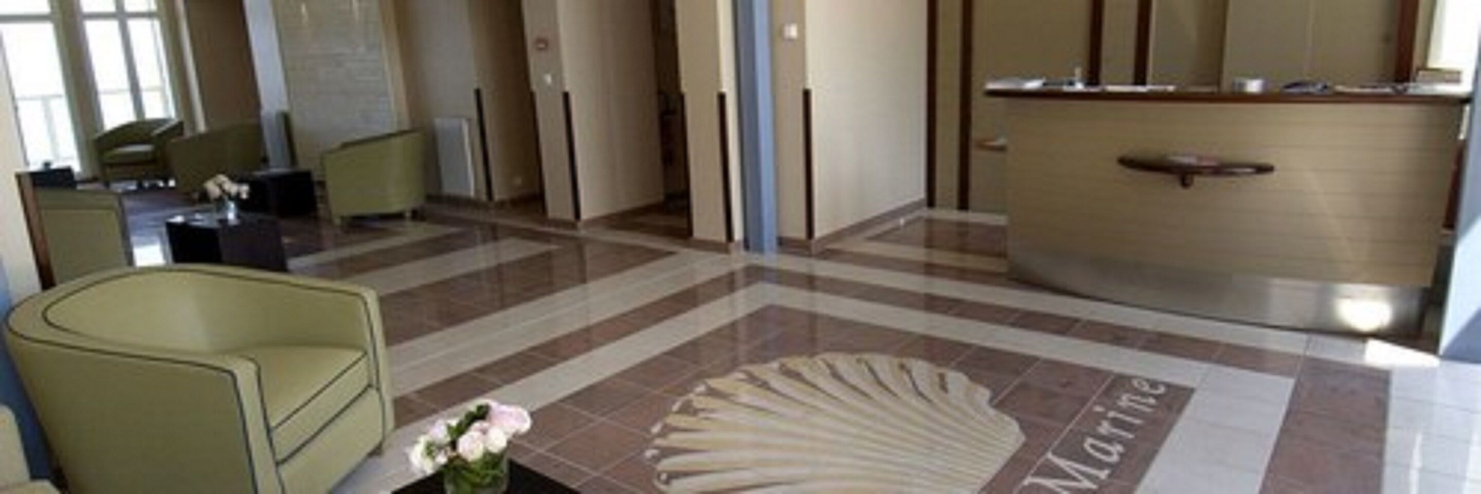 A lobby with a reception desk, a seating area, and a tiled floor with a marine-themed design.